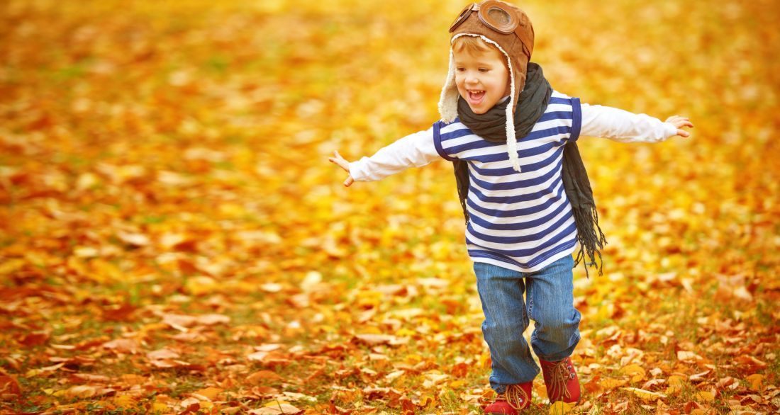 petit garçon courant sur les feuilles d'automne